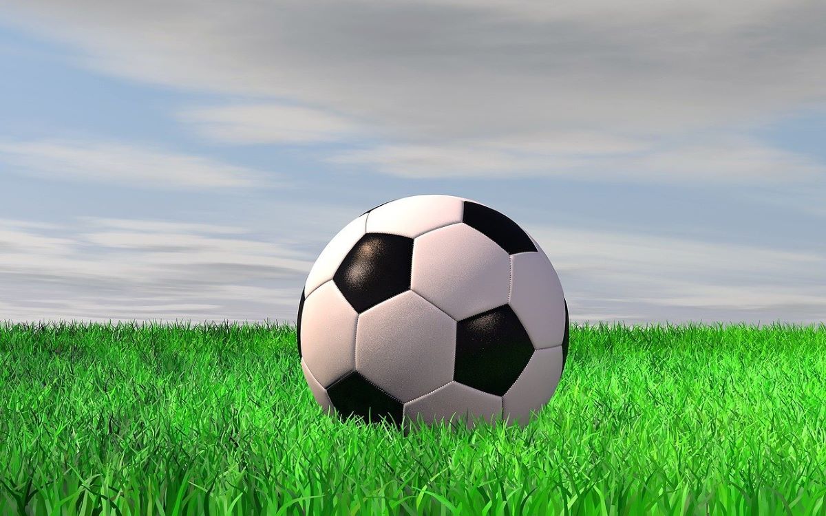 Illustration: Fußball auf grüner Wiese mit bewölktem Hintergrund - Beitragsbild für News im Juni 2024